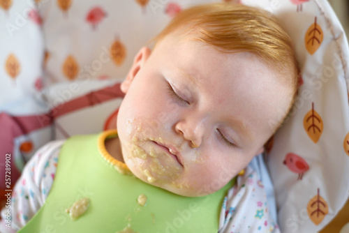 Fotografía mit brei verschmiertes baby schläft nach essen im hochstuhl
