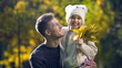 © motortion - Cheerful father holding cute daughter, strolling in autumn park, fatherhood