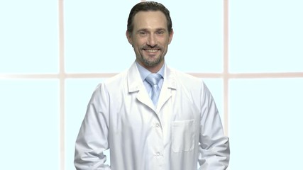 Wall Mural - Portrait of handsome mature man in lab coat. Smiling science specialist in white robe standing on checkered window background. People, occupation, lifestyle.