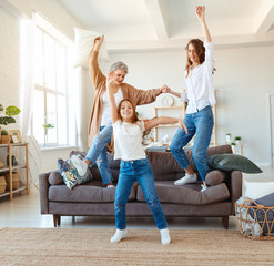 family three generations  grandmother, mother and child dancing, jumping and laugh at home.