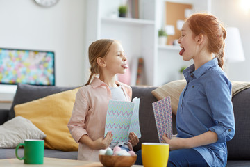 Side view portrait of two sisters sticking tongue out while teasing each other, copy space