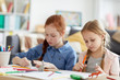 © Seventyfour - Portrait of two sisters drawing together sitting at table at home lit by warm sunlight, copy space