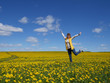 © Евгения Лекомцева - girl adult woman jumping on the field with yellow dandelions. In the blue sky of clouds. The girl is wearing jeans and a light sweater. Feeling of happiness and joy