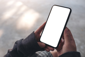 mockup image of a woman holding black mobile phone with blank desktop screen while sitting on the fl