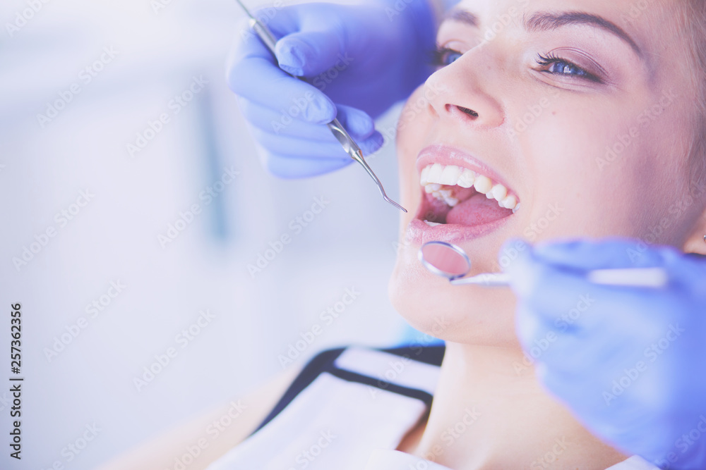 Young Female patient with open mouth examining dental inspection at dentist office.