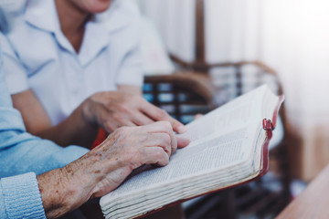 Wall Mural - Close up of old woman and her friends hold and reading bible together at home