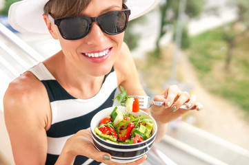 Woman eating salad. Beautiful woman eating salad with a view of the city