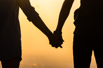 Silhouette hands of young couple at sunset.