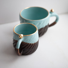 Two turquoise cups for tea or coffee on the white table