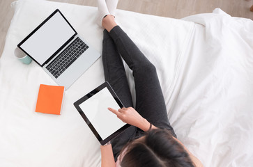 Poster - top view woman use tablet,laptp working online on bed in bedroom at home.mock up template device screen.Digital lifestyle concept.clipping path.