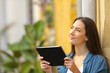 © Antonioguillem - Woman holding a tablet thinking looking at side