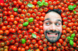 Mann mit Tomaten, Konzept für die Lebensmittelindustrie. Gesicht des lachenden Mannes in der Tomatenfläche.