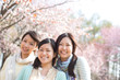 桜の前で微笑む3人の女性