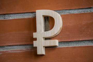 Wooden ruble symbol on brick wall background