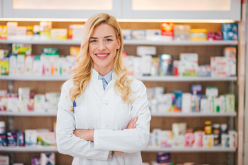 Wall Mural - Portrait of a smiling pharmacist with arms crossed at modern pharmacy.