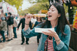 © PR Image Factory - Young beautiful asian japanese woman enjoying japanese snack tamagoyaki standing on walkway outdoor vendor festival. street food concept skewers grilled egg. female closed eyes eat delicious cuisine