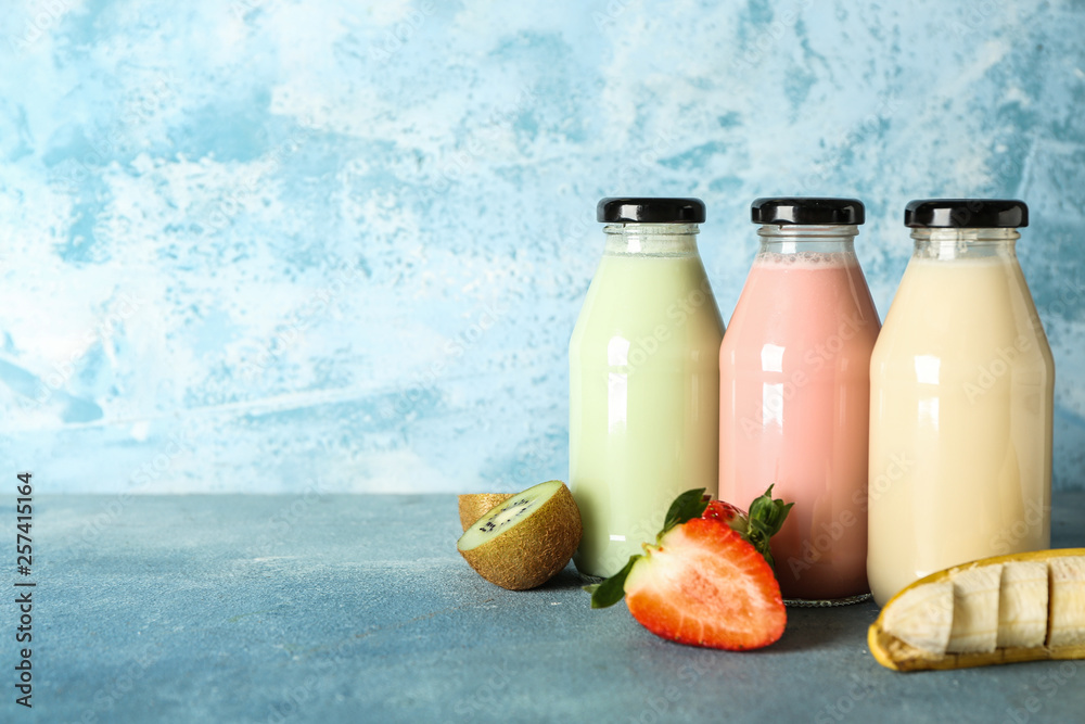 Bottles of healthy smoothie on color background