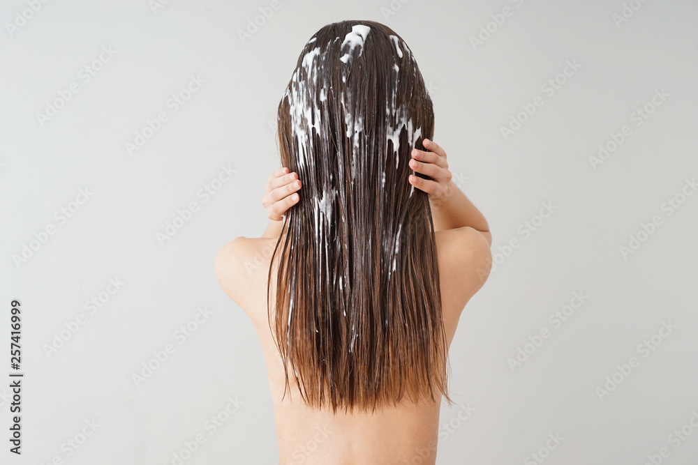 Woman using coconut oil for hair on white background