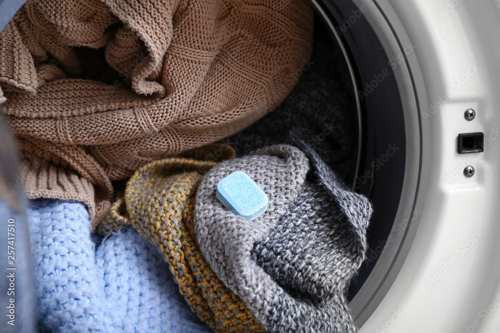 Modern washing machine with laundry and detergent, closeup
