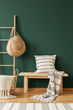 © Photographee.eu - Pillow on wooden stool next to ladder with bag in green living room interior with rug. Real photo