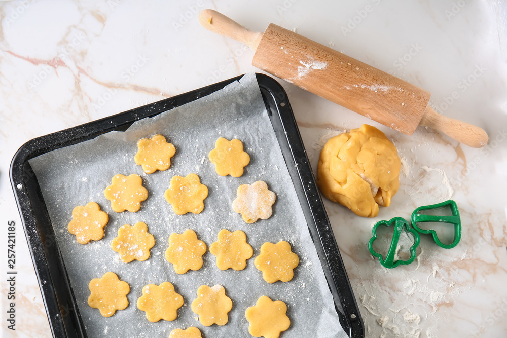 Baking sheet with raw cookies and rolling pin on light table