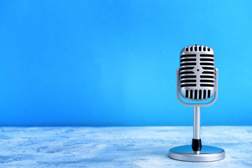 Retro microphone on table against color background