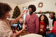 © Monkey Business - Couple Exchanging Gifts As Multi Generation Family Celebrate Christmas At Home Together