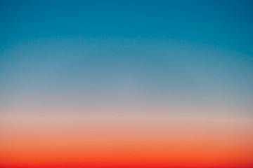 Wall Mural - predawn clear sky with red horizon and blue atmosphere. smooth orange blue gradient of dawn sky. bac