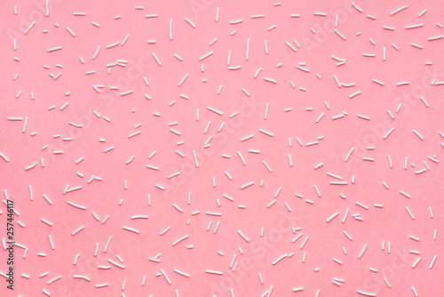 trendy pattern of white sprinkles over pink background, sugar sprinkle dots