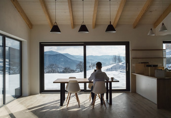 Wall Mural - Rear view of mature man sitting at the table in new home, using tablet.