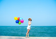 © nuiiko - Happy Asian woman in white dress holding colorful balloons on the beach, lifestyle concept.