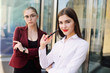 © Evgeniy Kalinovskiy - two young pretty business women against a modern glass office building