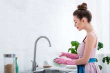 Pretty Young Woman In Pink Rubber Gloves Washing Dishes In Kitchen