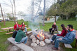 © Cavan Images - A group of 7 friends sit around a camp fire at a rustic resort.
