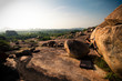 © Cavan Images - A solo, caucasian, male climber pulls onto his project boulder in Hampi, India.  Other than scattered bushes, the landscape is bare stone.  The horizon fades off into early morning haze in the distance.  Shot in the morning in Autumn (Fall).