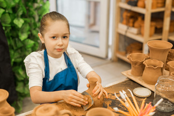 Poster - beautiful little girl making a pot of clay in a pottery workshop