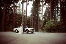 Bride And Groom Kiss In Front Of A Classic Car.