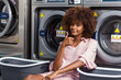 © Samuel B. - Young black African American woman waiting her clothes to be washed in a automatic laundry