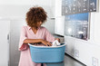 © Samuel B. - Young black African American woman holding a basket of clothes to be washed in a automatic laundry