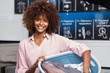 © Samuel B. - Young black African American woman holding a basket of clothes to be washed in a automatic laundry