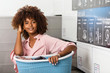 © Samuel B. - Young black African American woman holding a basket of clothes to be washed in a automatic laundry