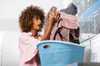 © Samuel B. - Young black African American woman holding a basket of clothes to be washed in a automatic laundry
