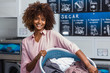 © Samuel B. - Young black African American woman holding a basket of clothes to be washed in a automatic laundry