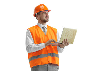 The builder in a construction vest and an orange helmet with laptop. Safety specialist, engineer, industry, architecture, manager, occupation, businessman, job concept