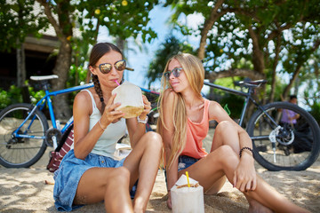 two female russian tourists drinking coconuts and having fun at beach on koh samui island thailand