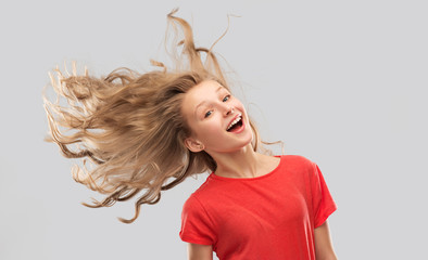 people concept - smiling teenage girl in red t-shirt with long hair waving over grey background