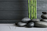 Fototapeta Dziecięca - Zen stones and bamboo on table against wooden background. Space for text