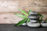 Fototapeta Desenie - Stacked zen stones and bamboo leaves on table against wooden background. Space for text