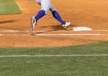 Low Section Of A Baseball Player Rounding First Base
