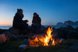 © Cavan Images - Two female travelers sitting around bonfire near lake